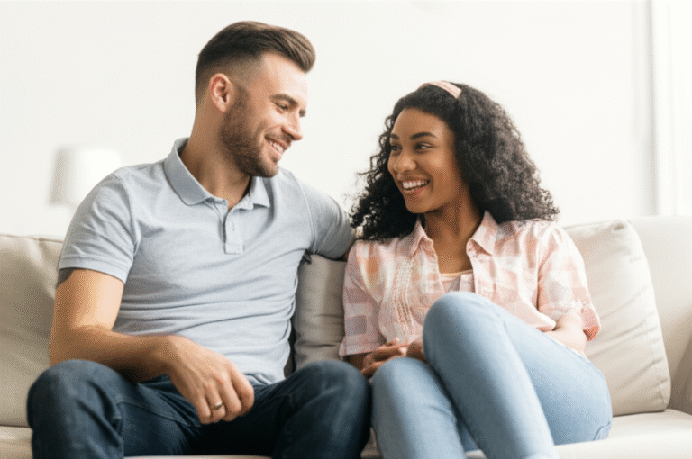 Casal sorrindo e conversando abertamente em um sofá